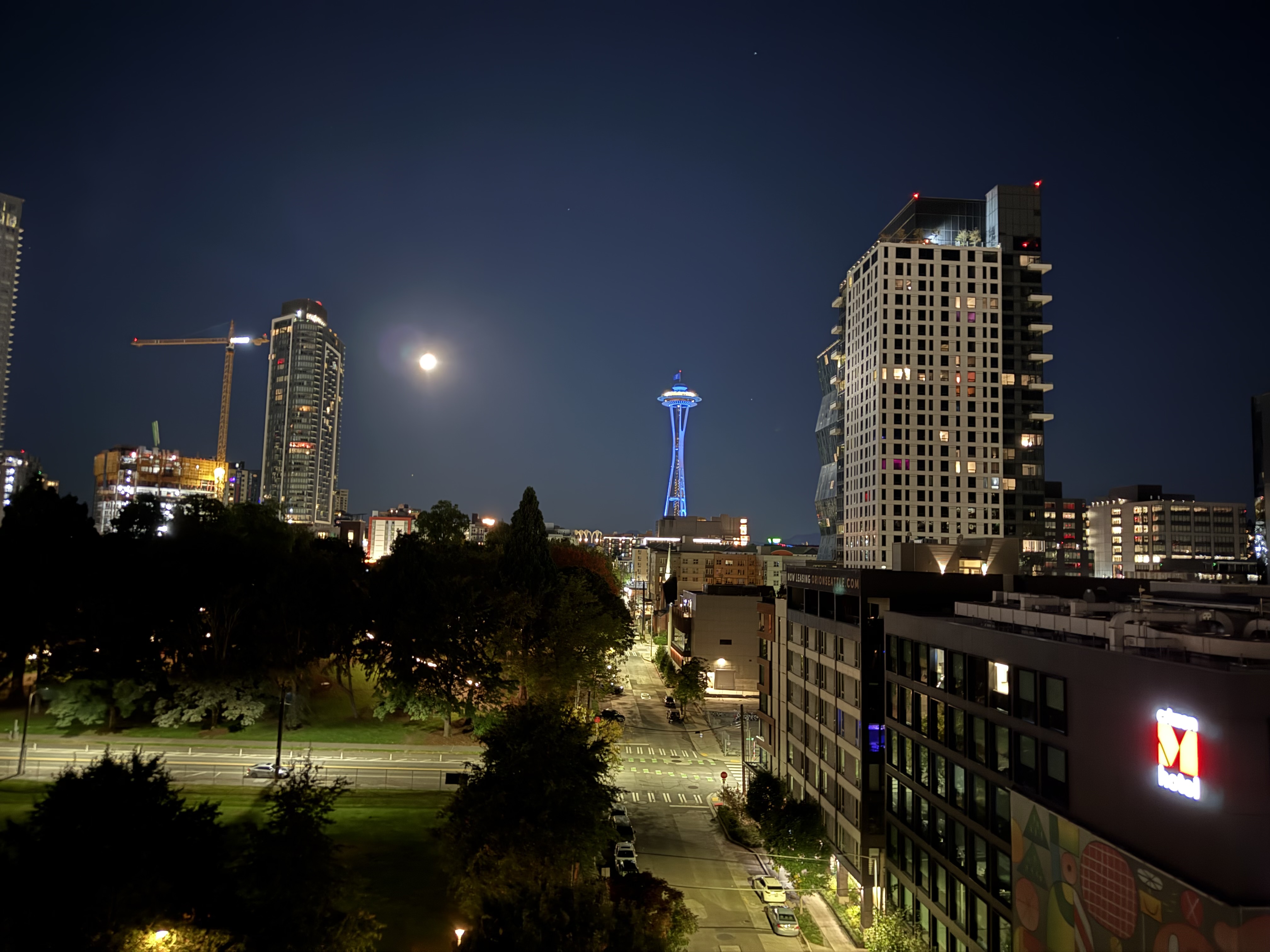 A bright moon and a Mariners themed Space Needle